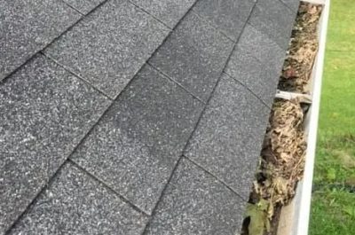 gutter Close-up of a roof with clogged gutters full of leaves, highlighting the need for professional gutter cleaning Kirkland to prevent water damage and improve home maintenance.